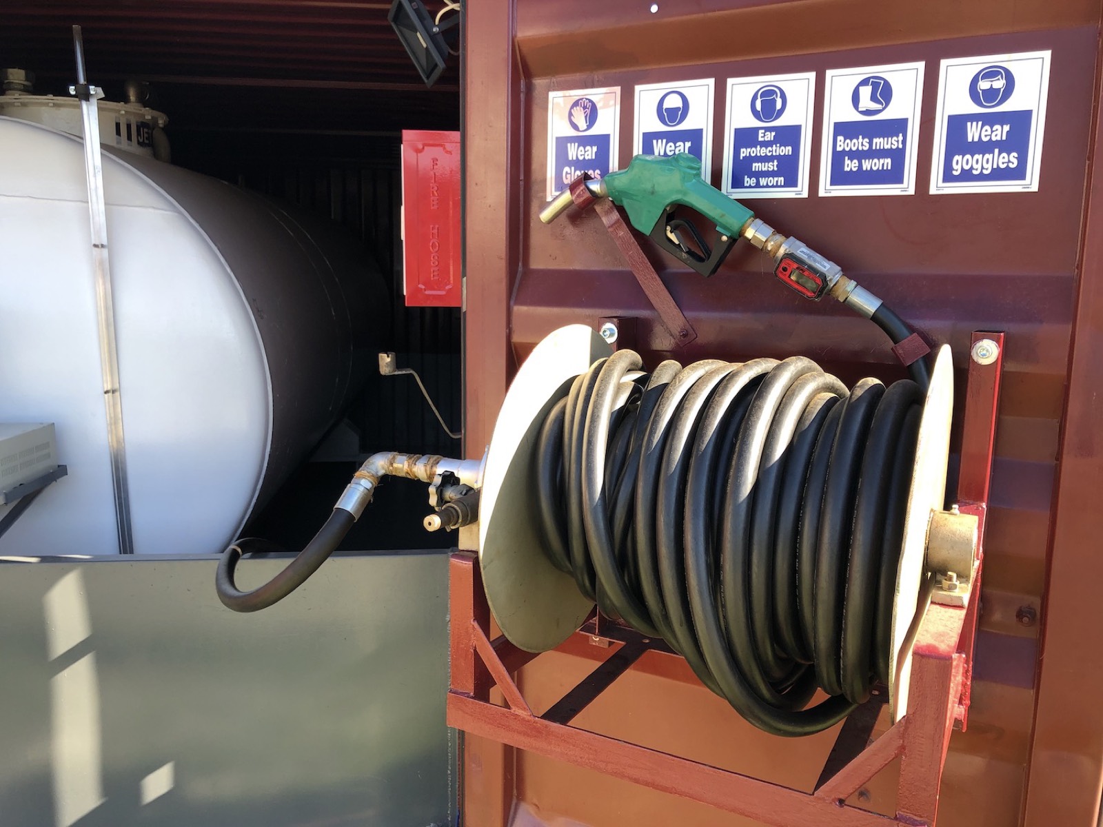Fuel hose reel and nozzle in a refuelling container
